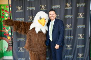 Principal Dr. Gabriel Cardenas poses with the Evergreen Eagle mascot.