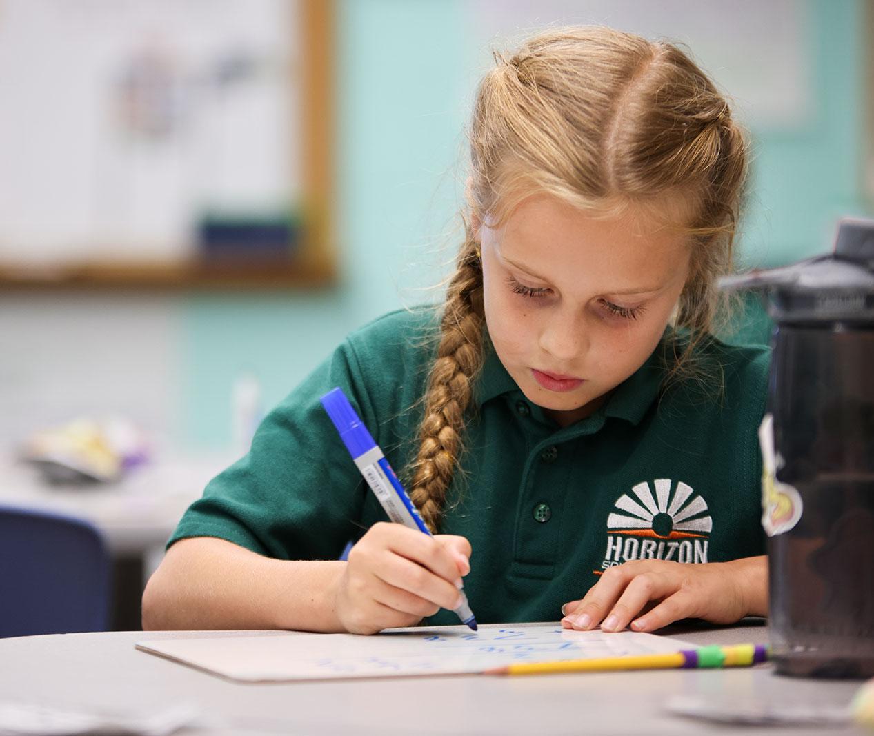 Student working on a notebook in a classroom.
