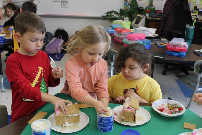 3 students working on building a gingerbread house