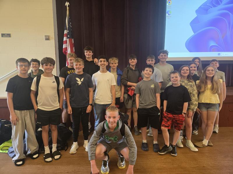 middle schoolers smile at the camera in banquet hall