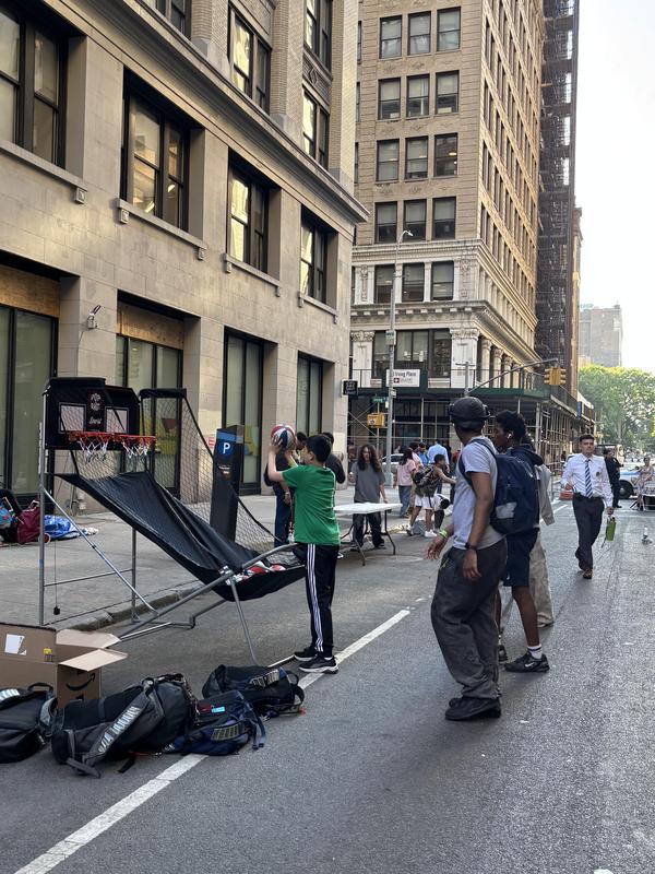 Group of young people playing basketball on a city street.