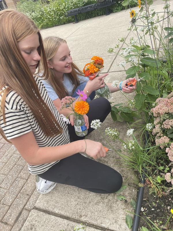 Two girls cut flowers at the garden.
