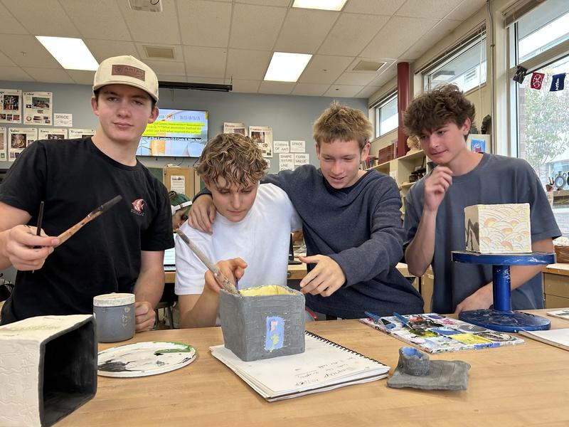 Four students in a Ceramics class apply glaze to slab-built boxes