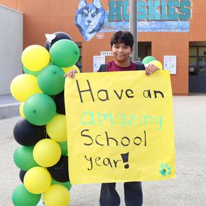 A boy holding a sign stating Have an amazing school year.