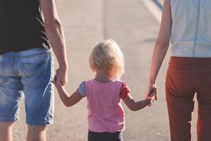 A couple holding hands with a child walks down a street