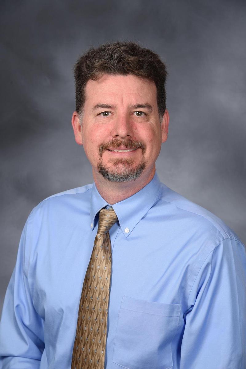 Jeff Brown has a goatee, short brown hair, and a tie.