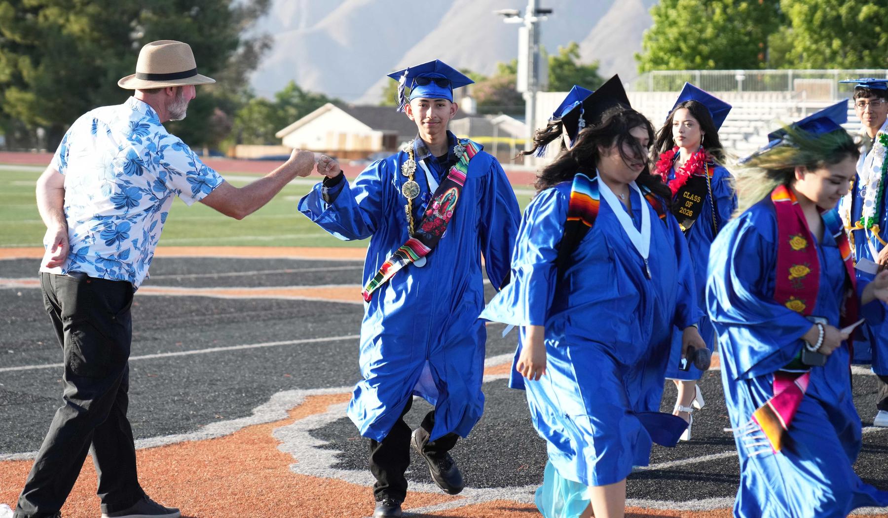 Staff member giving fist pumps to Mtn. View Graduates