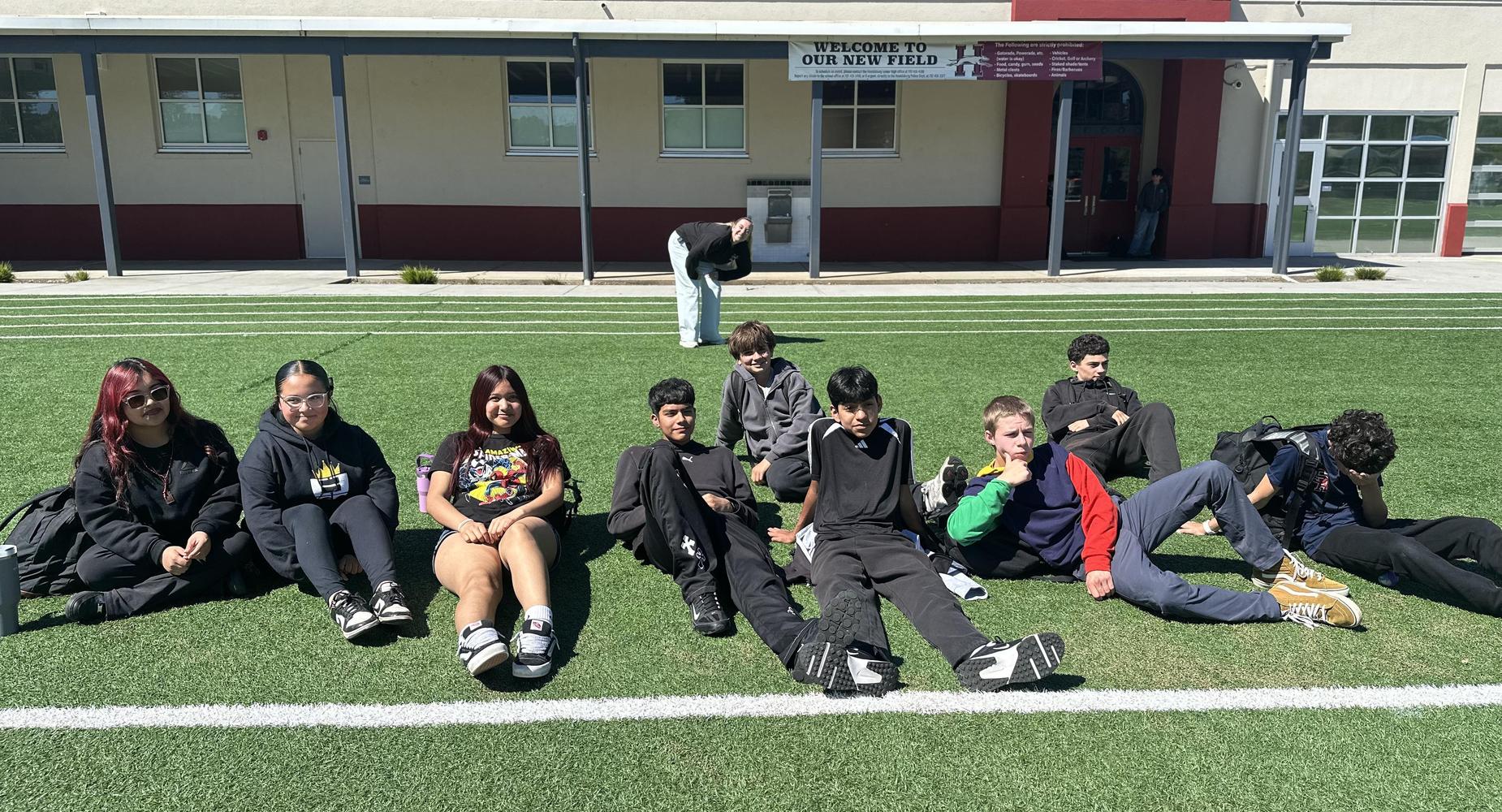 Students sitting together on the field in the sun