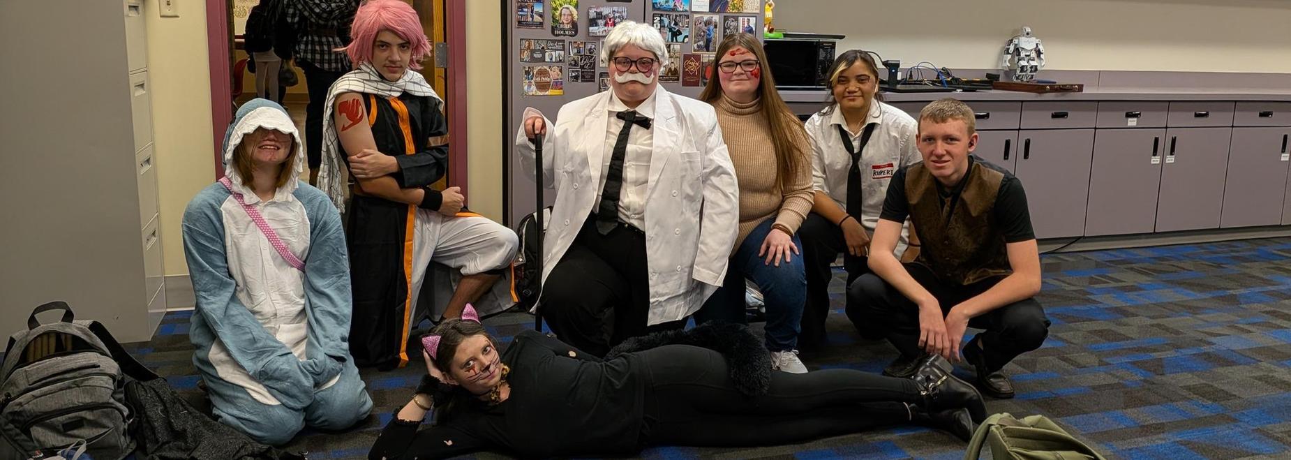 Group of cosplayers in various costumes posing together in a colorful setting.