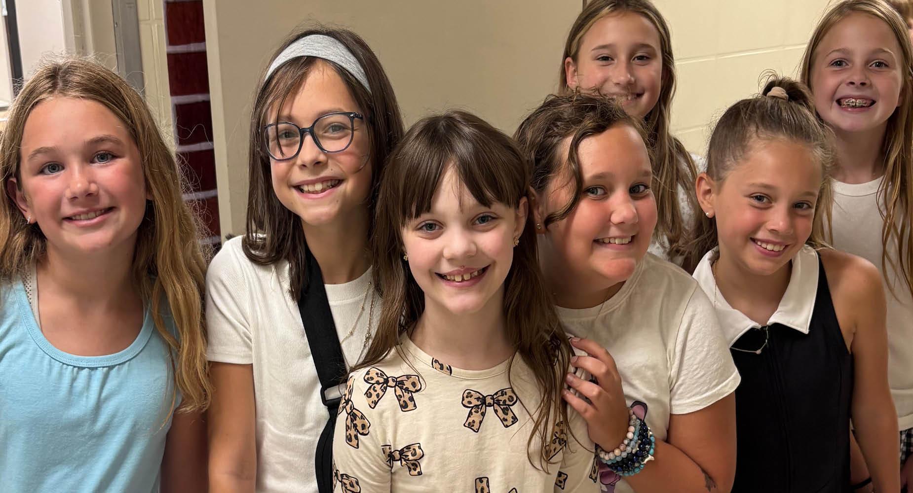A group of elementary students smile as they gather in the hallway on the first day of school 2025