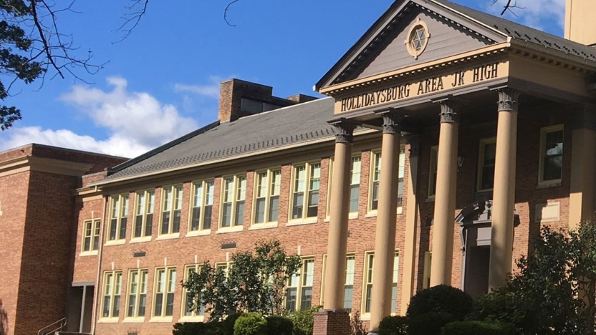 Historic brick building housing Hollidaysburg Area Jr High with greenery.