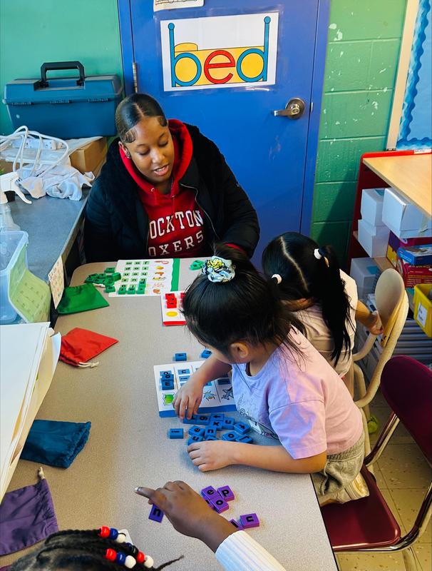 high school student works on activity with elementary schooler