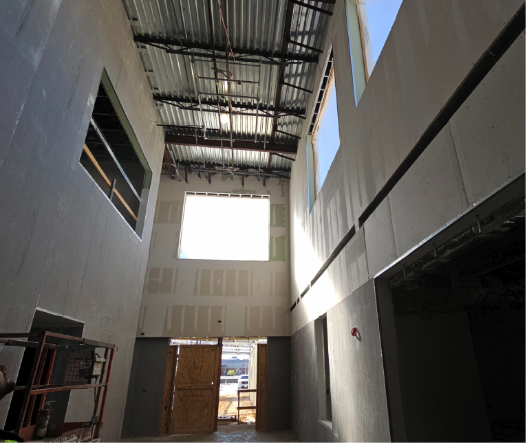 Interior of a building with large windows and unfinished walls.