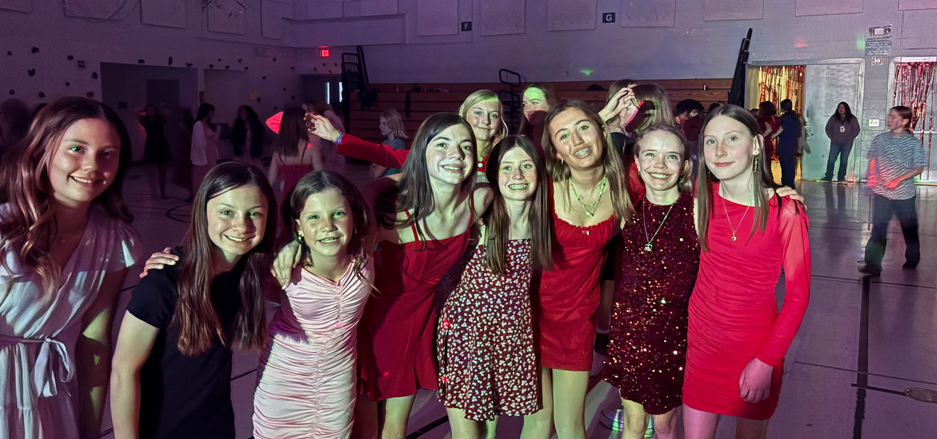 Girls in colorful dresses posing at a party, with lights and decorations in the background.