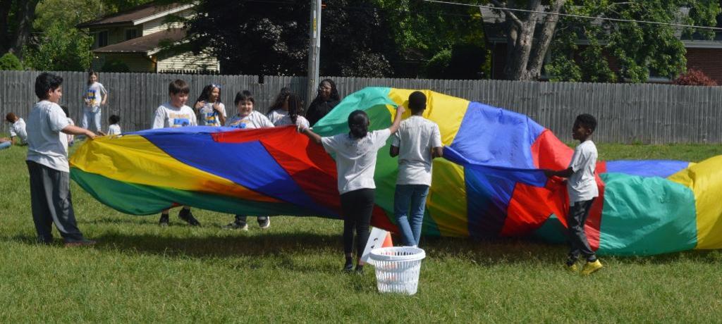 group of students play with giant brightly-colored parachute