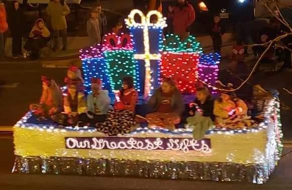 Float with students seated in front of packages outlined with lights