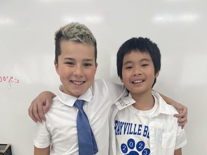 Two boys posing with arms around each other, dressed in school shirts.