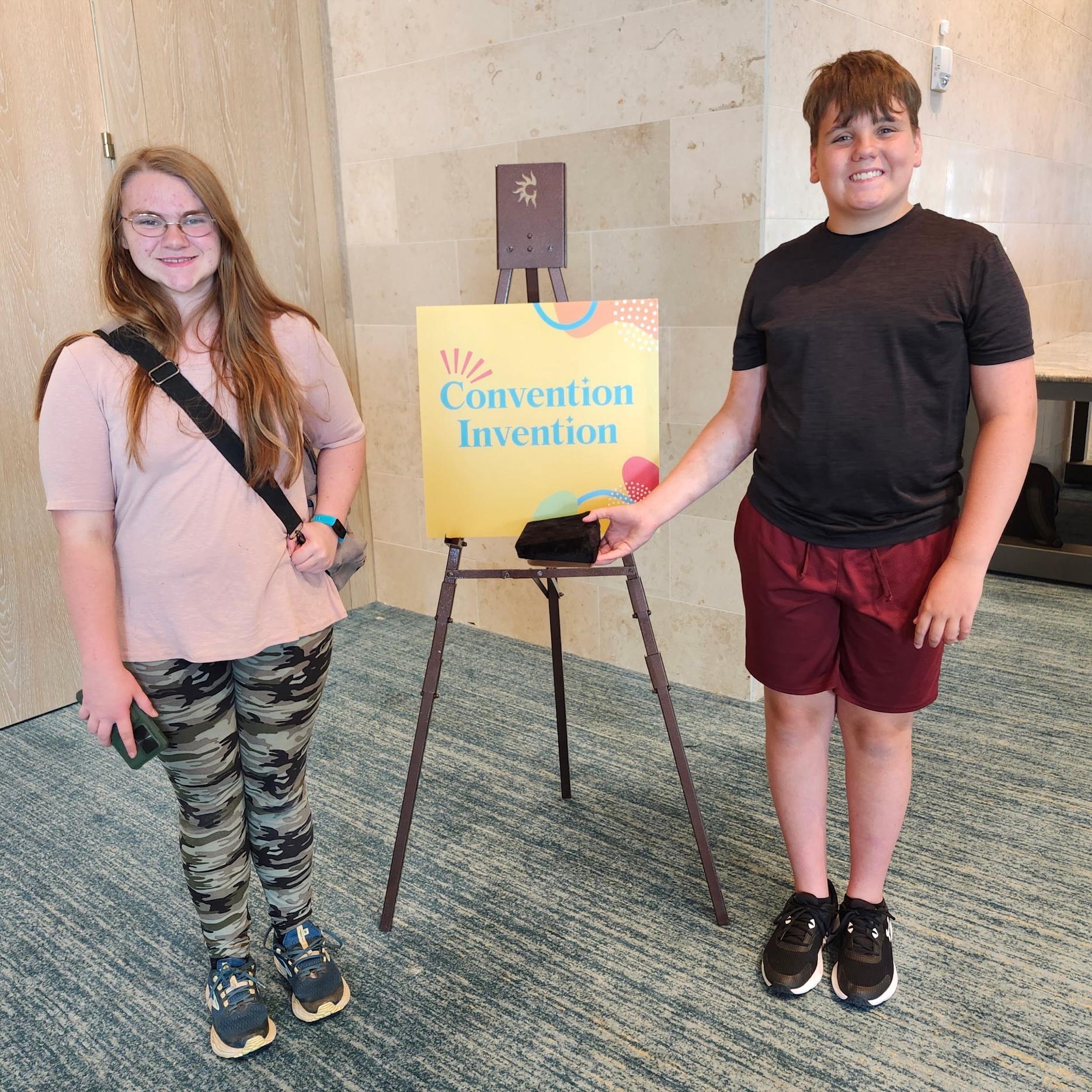 Two students standing with sign in hotel. 