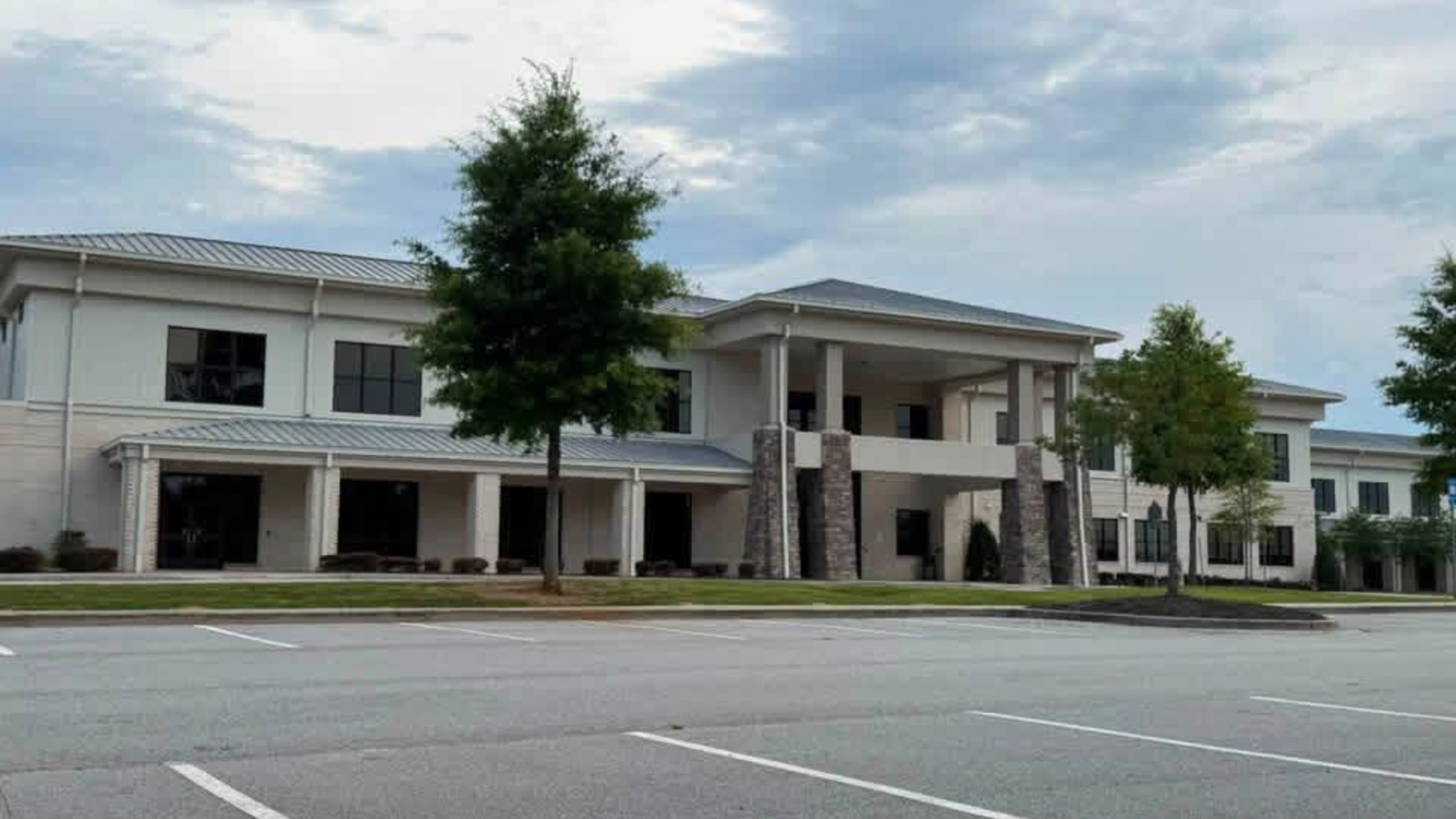 Modern corporate building with stone accents and trees in the front.