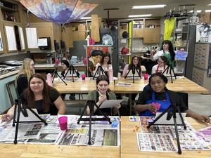 A group of artists painting in a vibrant studio setting with easels and supplies.