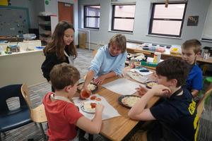 Students work with one of the volunteer grandmothers to make personal pizzas.