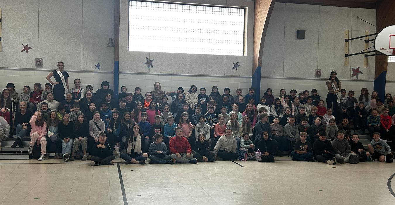 A large group of students and teachers posing in a gymnasium for a photo.