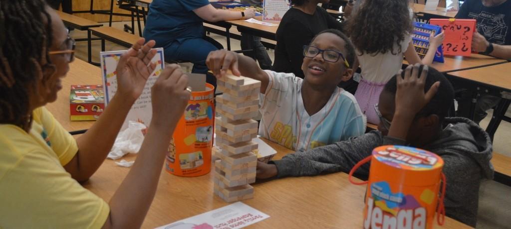 mom laughs as boy remove game piece from Jenga tower