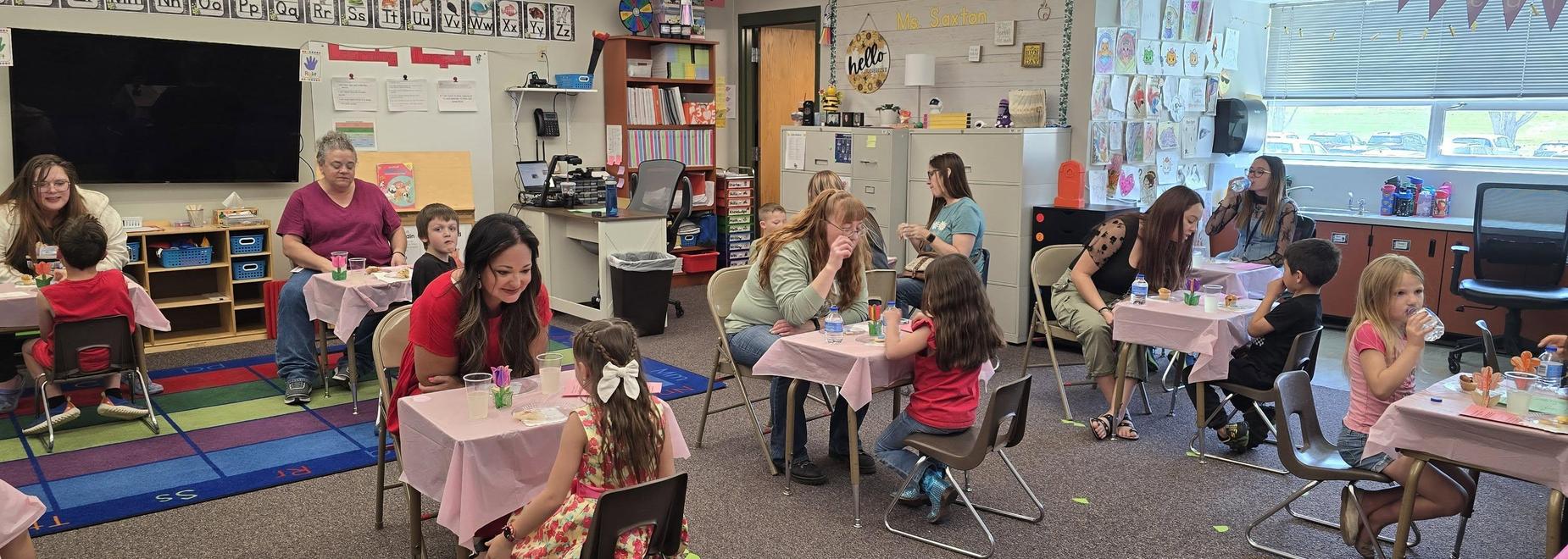 Another classroom scene with children and adults interacting at tables.