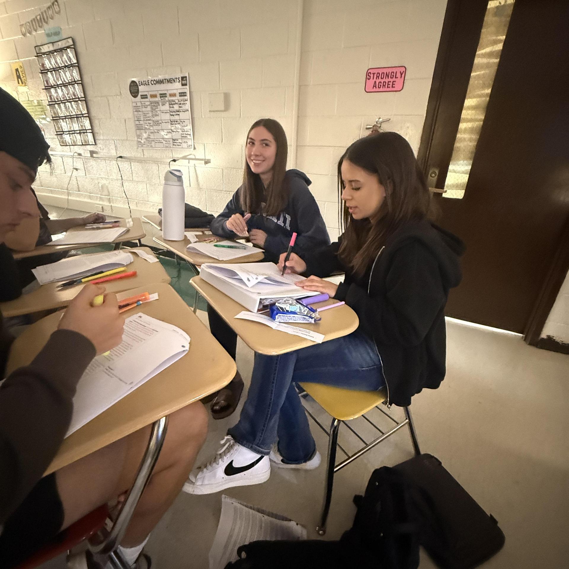Students engaged in group study at desks with books and writing tools.