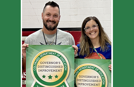 Man and woman stand holding award posters