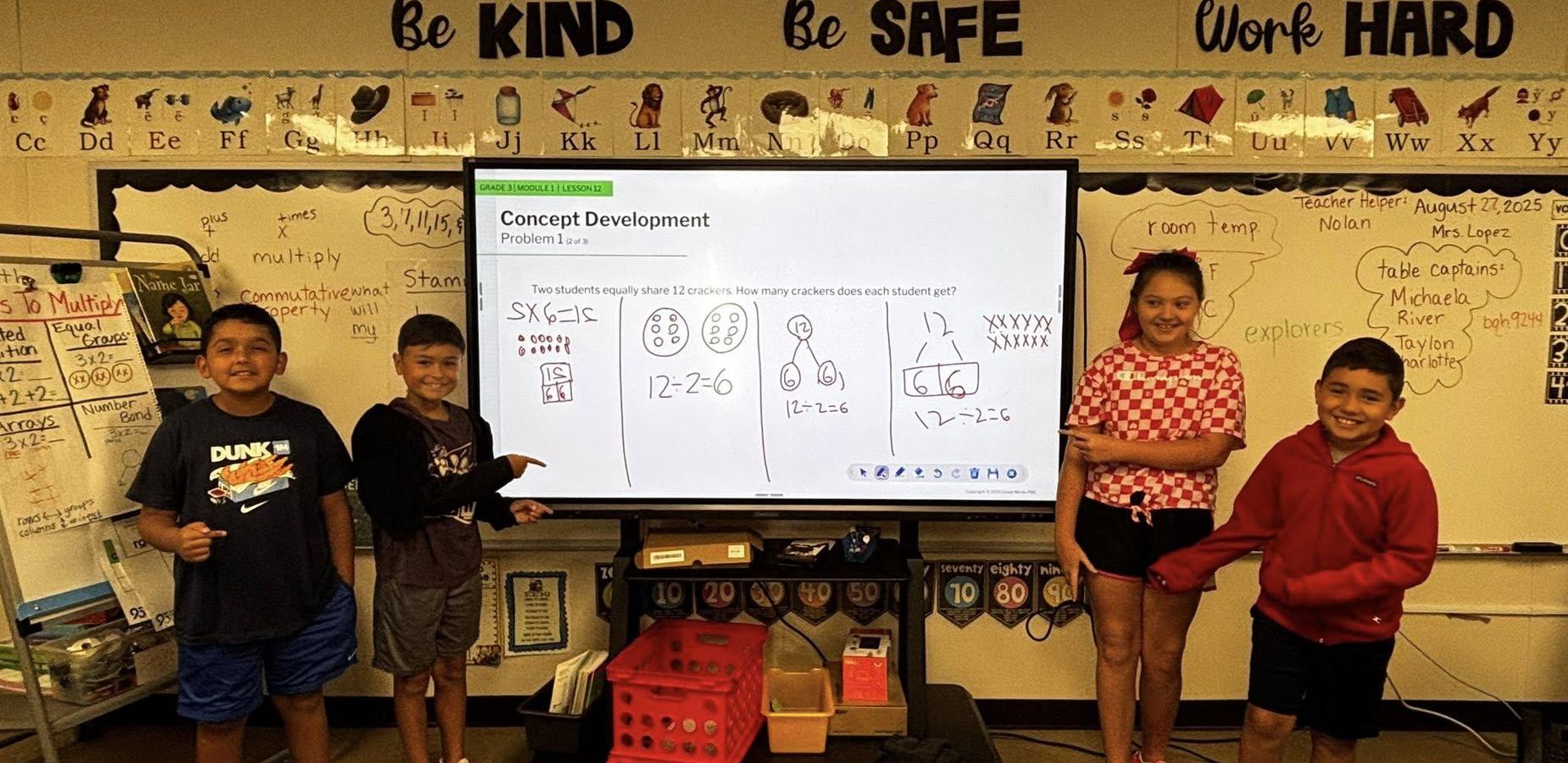 Two boys in black shirts standing on one side of view sonic screen; girl in pink and white shirt, boy in red shirt on other side of screen; all pointing at screen