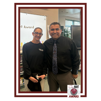 Two people standing together in a library setting, smiling and posing for a photo.