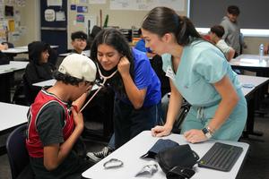 student listening to heartbeat of classmate with a nurse watching