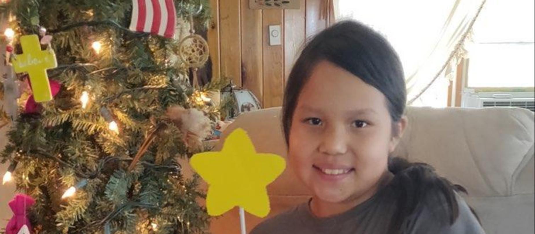 girl standing beside a decorated tree smiling
