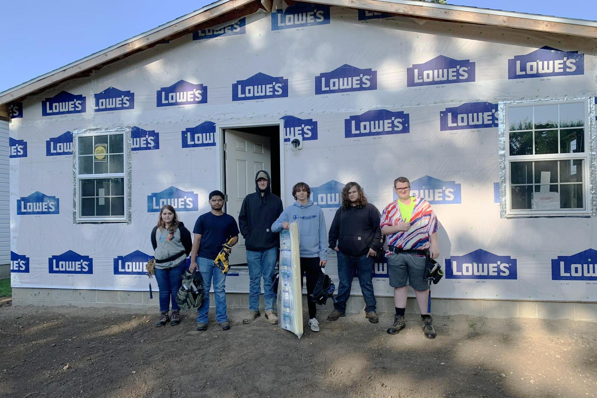 GRCC construction students pose for a photo in front of a structure they are building.