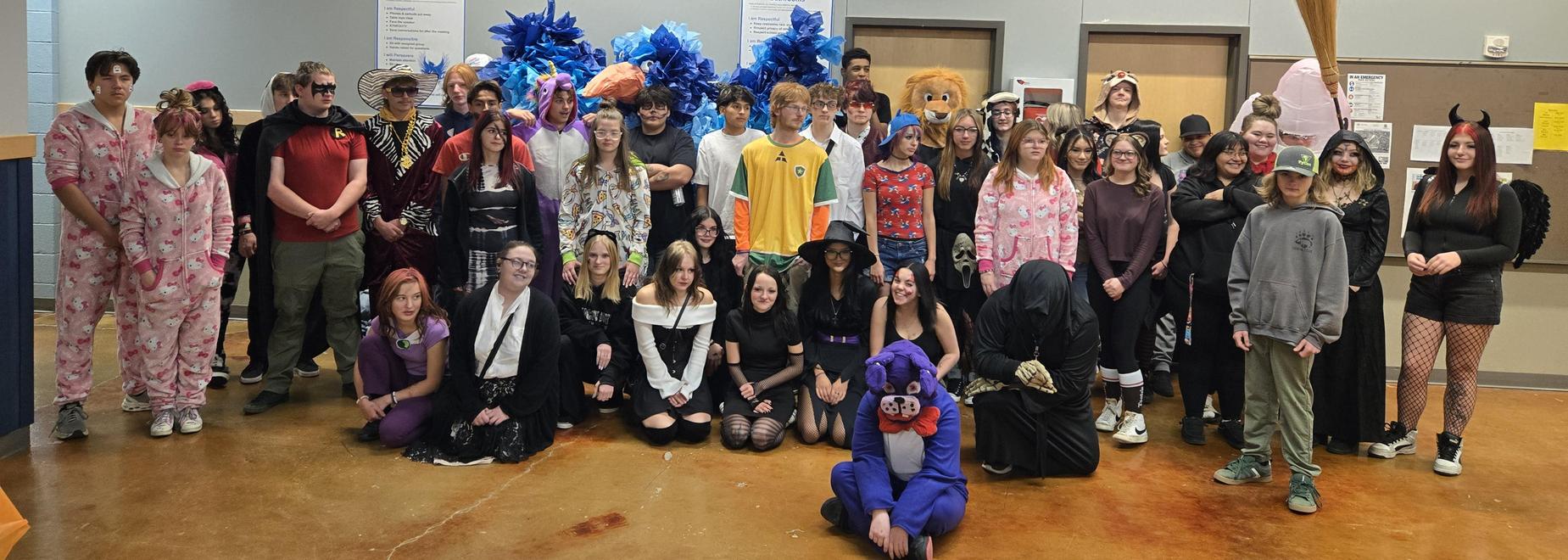 A diverse group of students in costumes posing together at a school event.