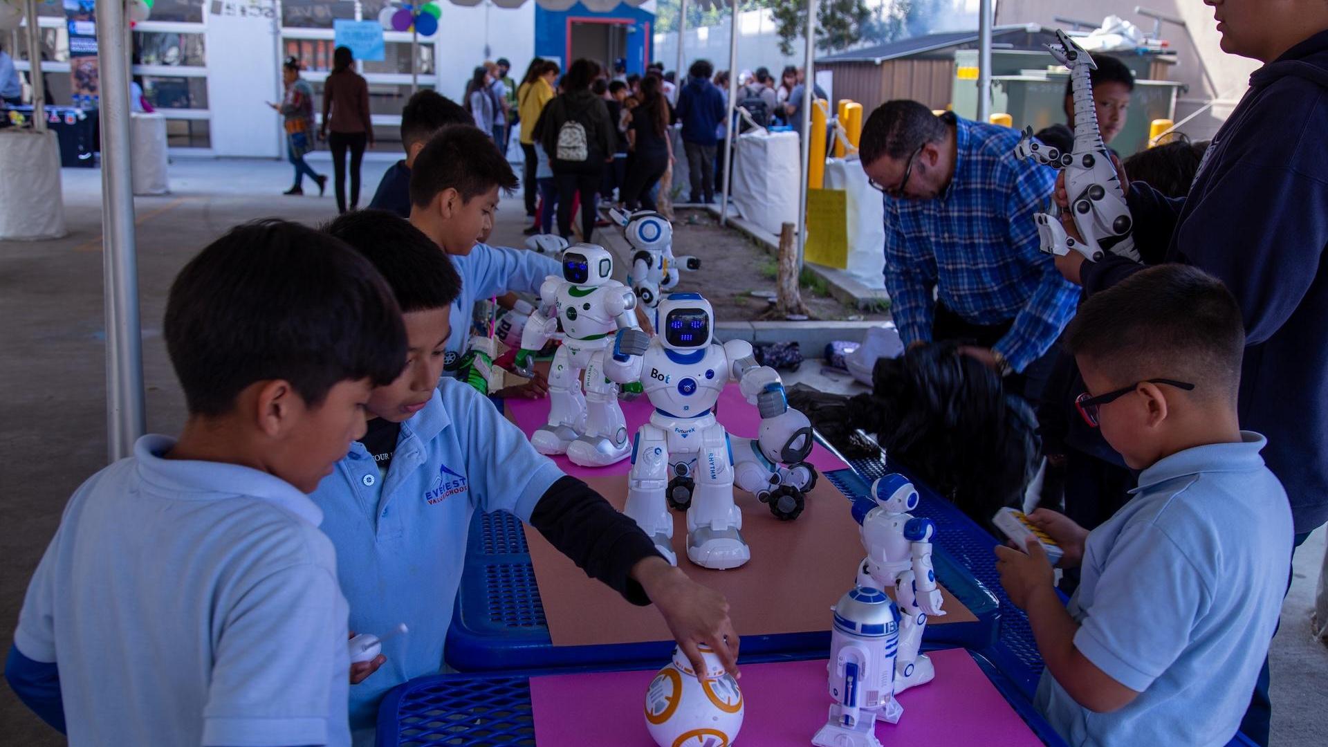 Children interact with robots at a school event, exploring technology and creativity.