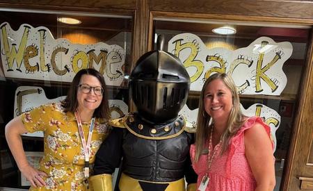 Two women pose with a knight mascot.