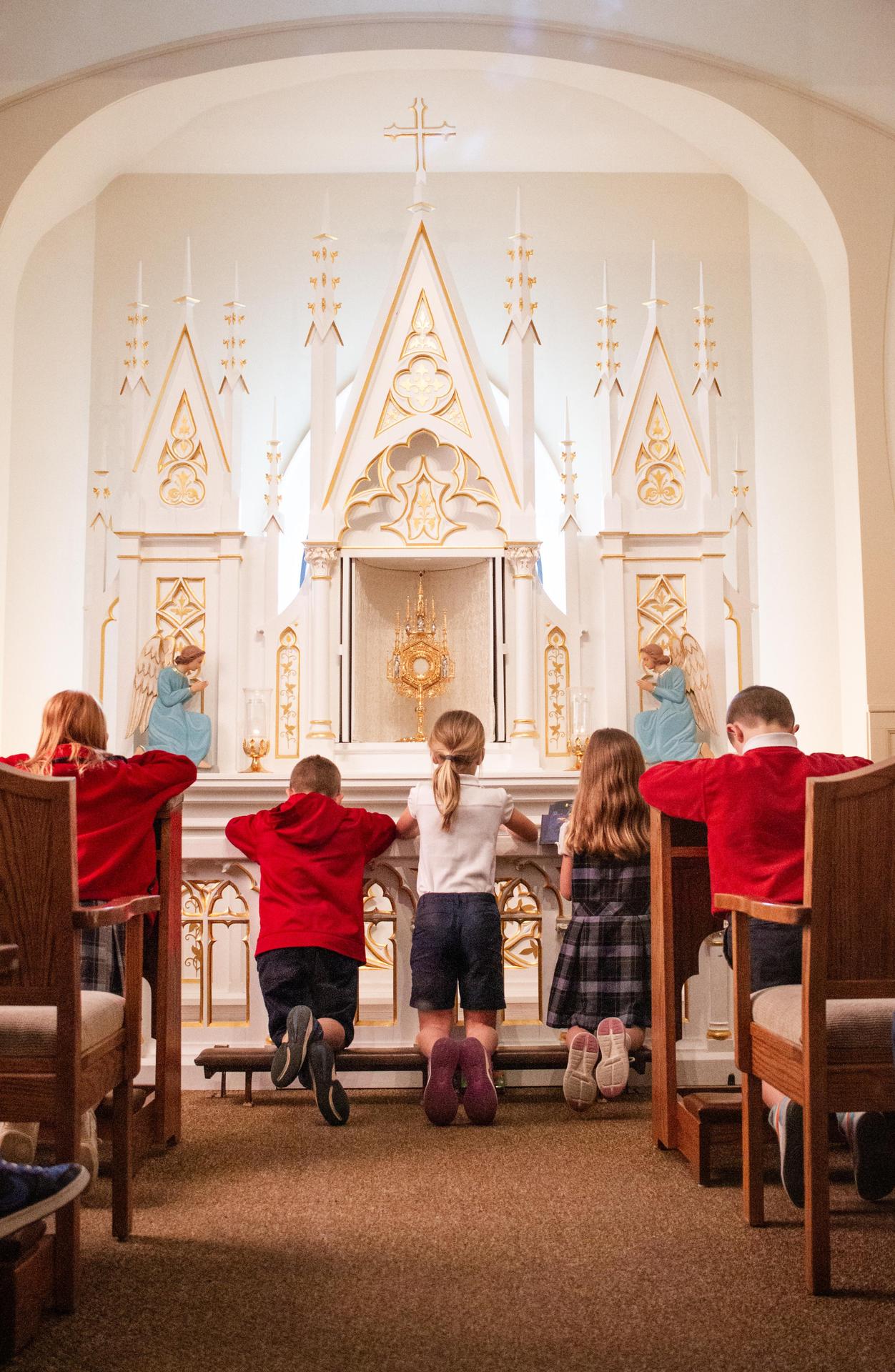 Students praying while kneeling at the altar.