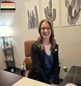 Image of woman sitting at a desk smiling with images of cactus in the background.