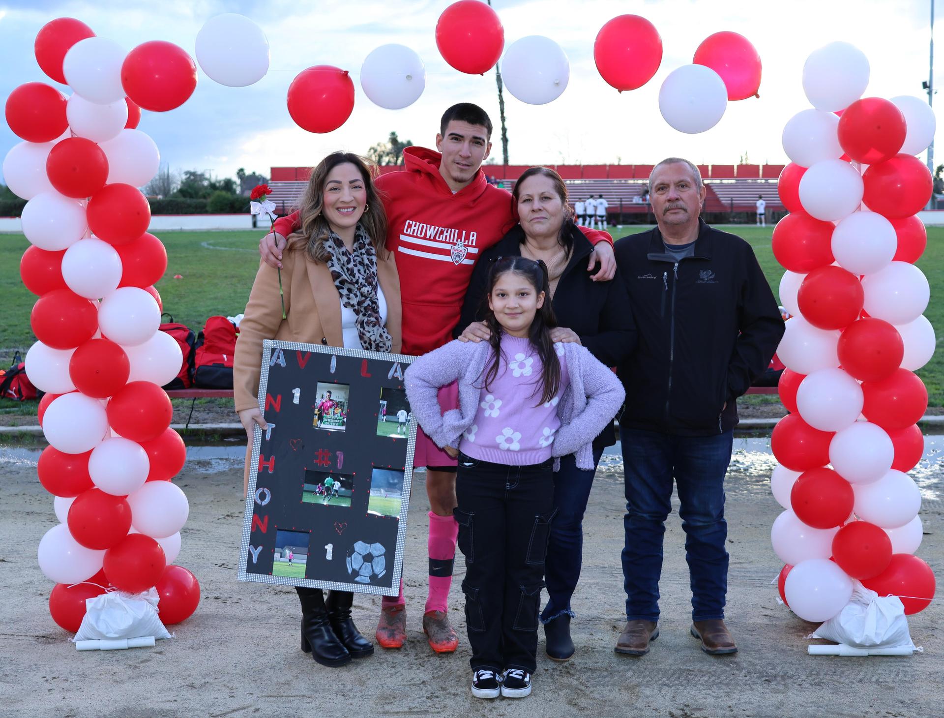 seniors and their escorts posing beneath a balloon arch