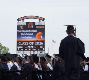 A graduate in front of the scoreboard.