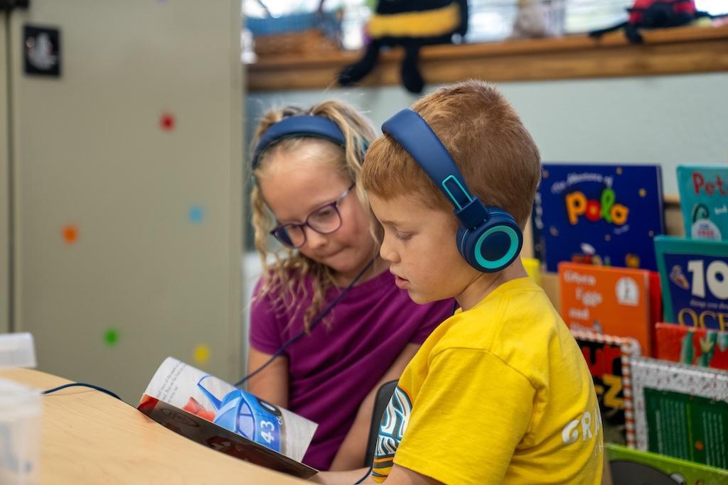 two students listening to a story with headphones on
