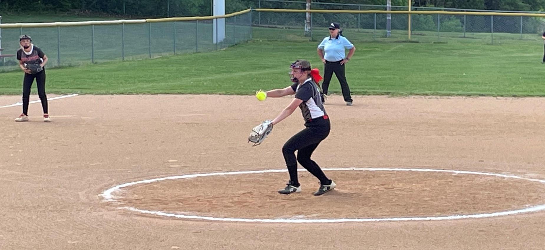 A softball player throws a pitch.
