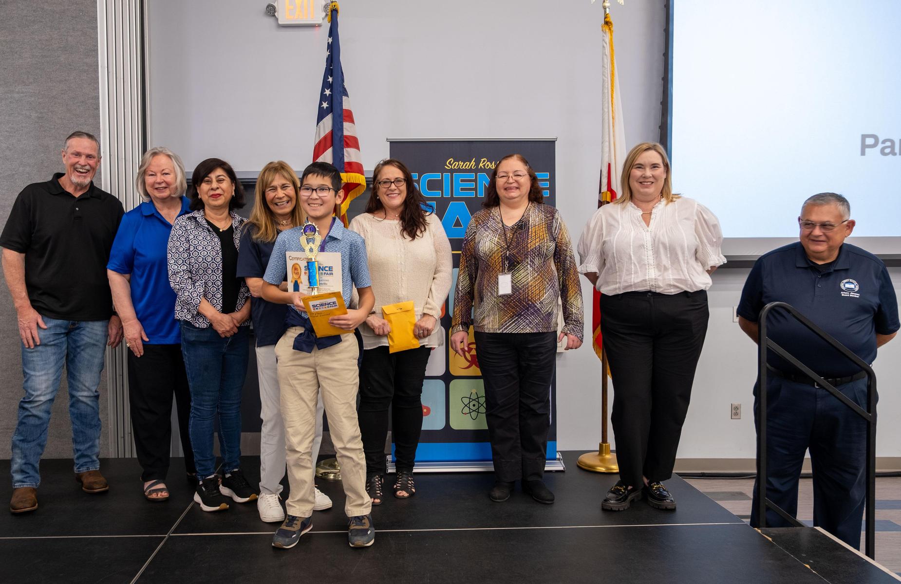 student with 2nd place trophy and certificate with school board