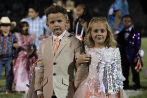 Two young children in formal attire standing together at an event.