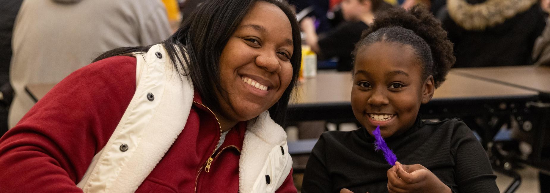 A mother and daughter smile while doing arts and crafts