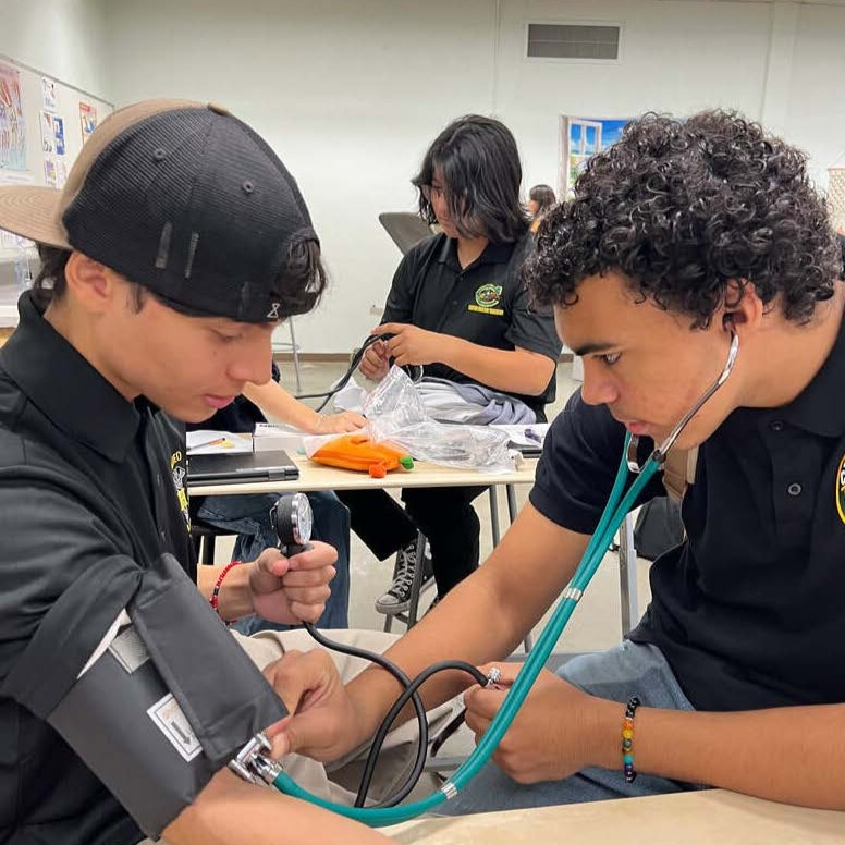 Students practice taking blood pressure in a classroom.