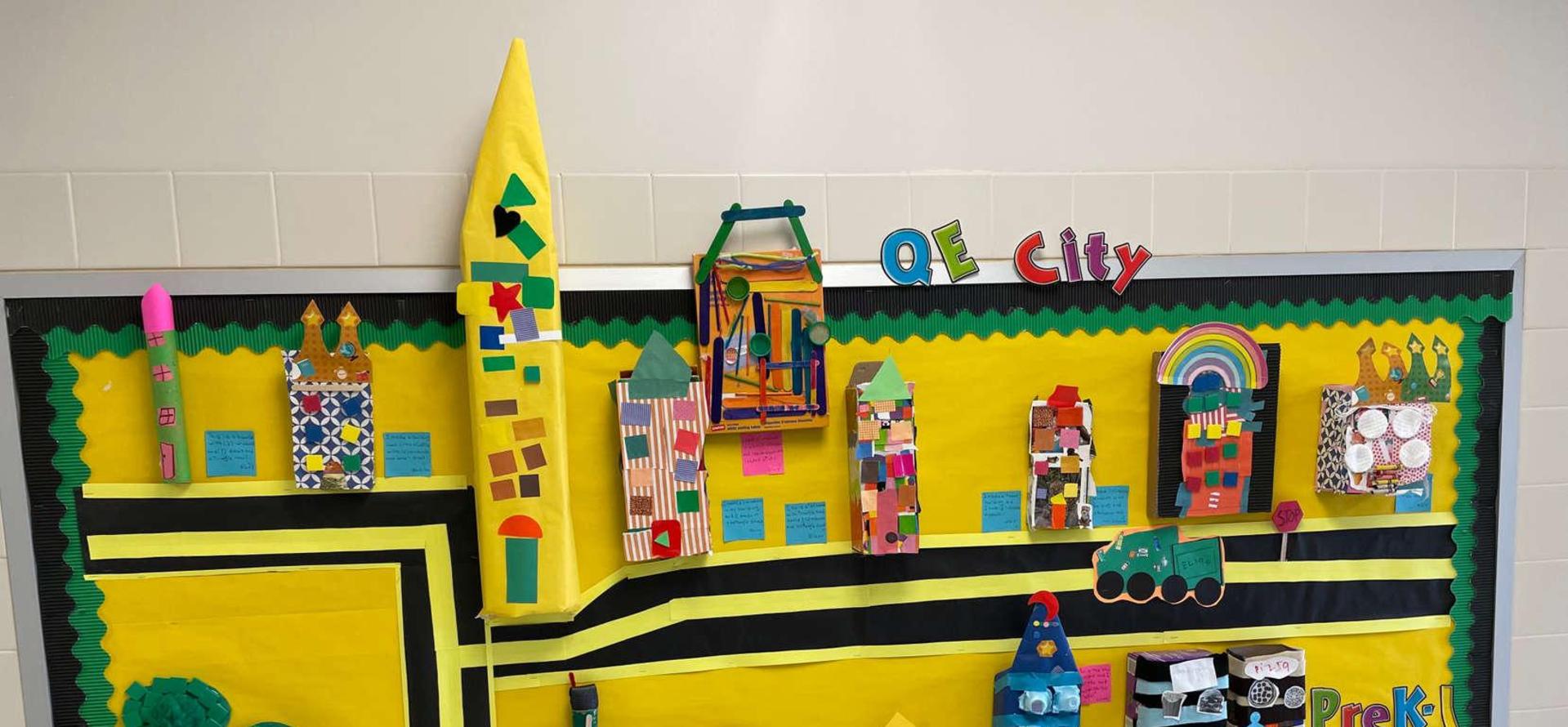Colorful bulletin board displaying a model city with various crafts and decorations.