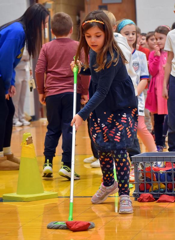 a girl pushing a bean bag with a dust mop